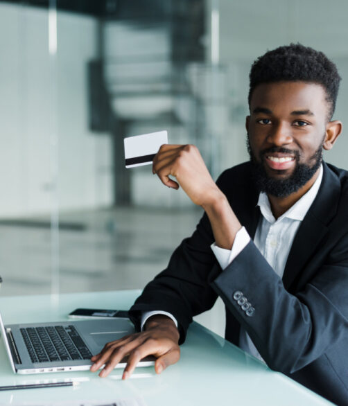 african-man-talking-phone-reading-credit-card-number-while-sitting-office